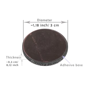 May include: A round, dark brown shungite stone with a diameter of approximately 1.18 inches (3 cm) and a thickness of about 0.12 inches (0.3 cm). The stone has an adhesive base and the text "SHUNGITE ZAZHOGINO" is visible.