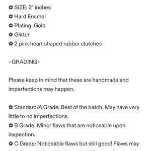 May include: Text description of a product, including size, materials, and grading. The product is 2 inches in size, made of hard enamel with gold plating and glitter. It includes two pink heart-shaped rubber clutches. Grading information is also provided.