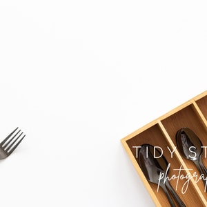 Peut inclure: Un tiroir à couverts en bois avec des couverts en métal noir, y compris des fourchettes, des cuillères et un couteau. Le tiroir est sur une surface blanche. Le texte "TIDY STOCK photography" est visible sur le tiroir.