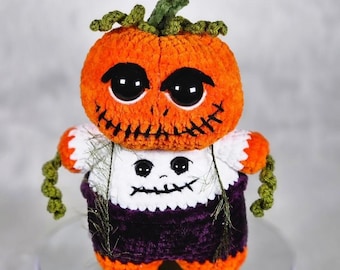 May include: A handmade Halloween-themed crochet doll. The doll features an orange pumpkin head with large black eyes and a stitched mouth. It wears a white shirt with a spooky face and a purple skirt. Green vines serve as arms and a stem.