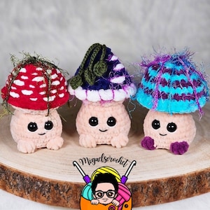 May include: Three crocheted mushroom plushies with different colored hats. The mushrooms are pink with black eyes and a smiling mouth. The hats are red and white striped, blue and purple striped, and purple and white striped.