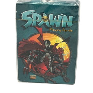 May include: A deck of Spawn playing cards in a teal box. The front features the Spawn logo with a skull icon, the text "Playing Cards," and an illustration of the character Spawn wearing a red cape and black suit, surrounded by a metal chain.