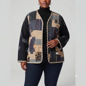 May include: A long-sleeve open-front jacket featuring a patchwork design with various blue, black, and tan fabric squares. The garment includes a light-colored striped trim along the edges, a black turtleneck base layer, and dark blue denim jeans.