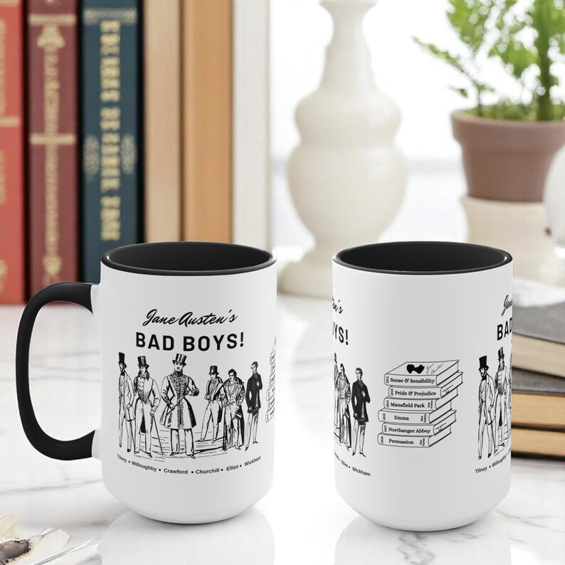 Pu&ograve; includere: Due tazze in ceramica bianca con bordi neri. Le tazze presentano un'illustrazione in bianco e nero di uomini dai romanzi di Jane Austen con il testo "Jane Austen's Bad Boys!" e un elenco dei nomi dei personaggi. Le tazze sono su una superficie bianca.