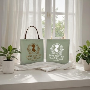 May include: Two sage green tote bags with brown and cream handles. Each bag features a silhouette of Jane Austen within a laurel wreath, with the text "JANE AUSTEN 250" and the years "1775-2025" or "1775-2035". The bags are displayed near potted plants.
