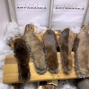 May include: Five brown fur insoles on a wooden surface. The insoles are made of real fur and are designed to be used in shoes or boots. The fur is soft and fluffy, and the insoles are a good way to add warmth and comfort to your footwear.