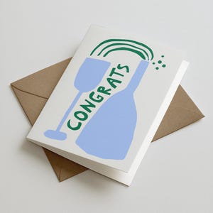 Könnte beinhalten: Glückwunschkarte mit einer Illustration einer blauen Weinflasche und eines Glases, mit dem Wort "CONGRATS" in Grün. Die Karte befindet sich auf weißem Hintergrund, mit einem braunen Umschlag darunter.