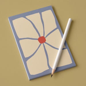 Può includere: Un blocco note rettangolare con un motivo floreale e una matita bianca. Il blocco note ha un bordo azzurro e un motivo floreale color crema con un centro rosso. La matita è posizionata diagonalmente sul blocco note.