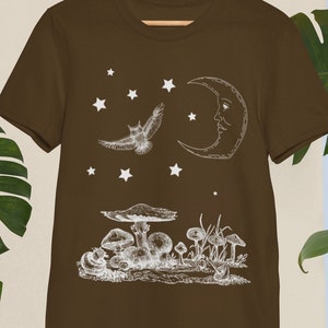May include: A brown t-shirt with a white graphic of a crescent moon, an owl flying, and mushrooms. The graphic is in a vintage style.