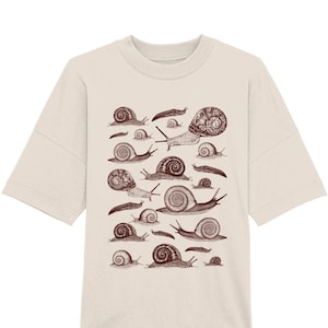 May include: A beige t-shirt featuring a brown illustration of various snails.