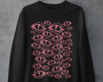 May include: Black sweatshirt featuring a pink eye pattern graphic print. The eyes are stylised and have a creepy, almost menacing look.