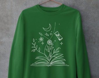May include: A green sweatshirt with a white graphic design of an open book with a flower, moon, stars, and an hourglass.