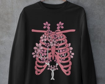 May include: Black sweatshirt featuring a pink floral design within a ribcage graphic.