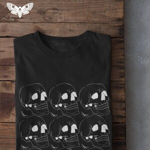 May include: Black t-shirt with a white skull pattern. The skulls are arranged in rows and are surrounded by small white butterflies.