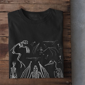May include: Black t-shirt with a white print of various animal skeletons, including a bat, a bird, and a lizard.