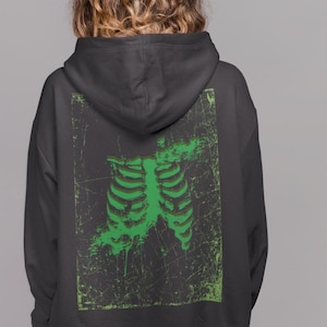 May include: Black hooded sweatshirt with a green ribcage graphic on the back.
