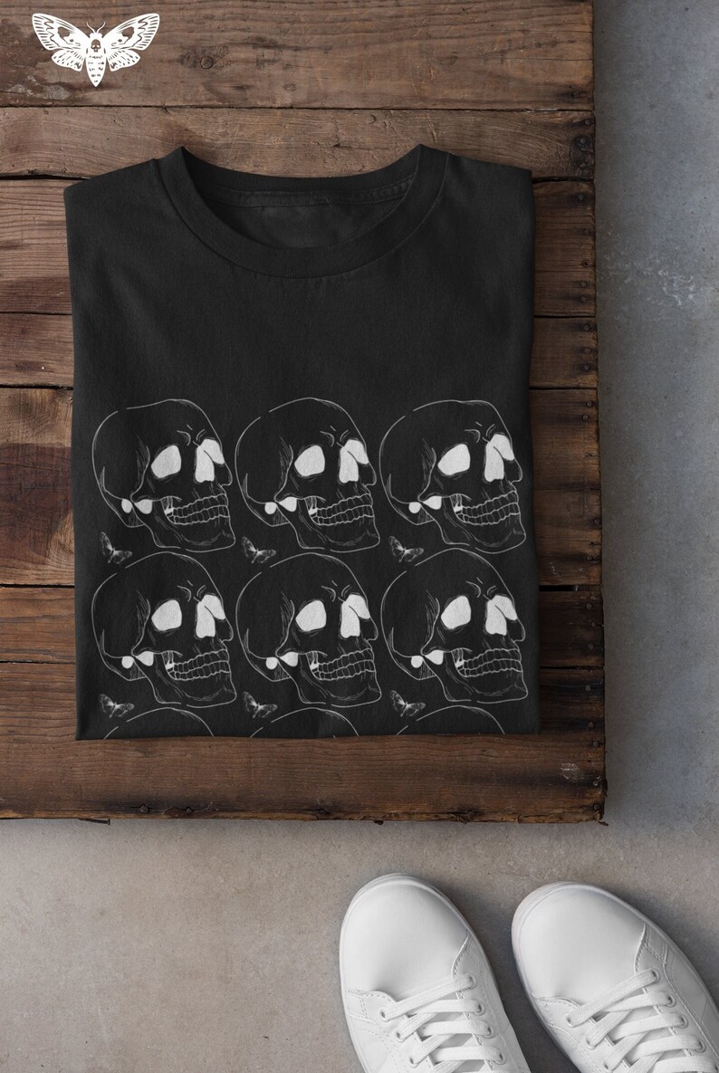 May include: Black t-shirt with a white skull pattern. The skulls are arranged in rows and are surrounded by small white butterflies.