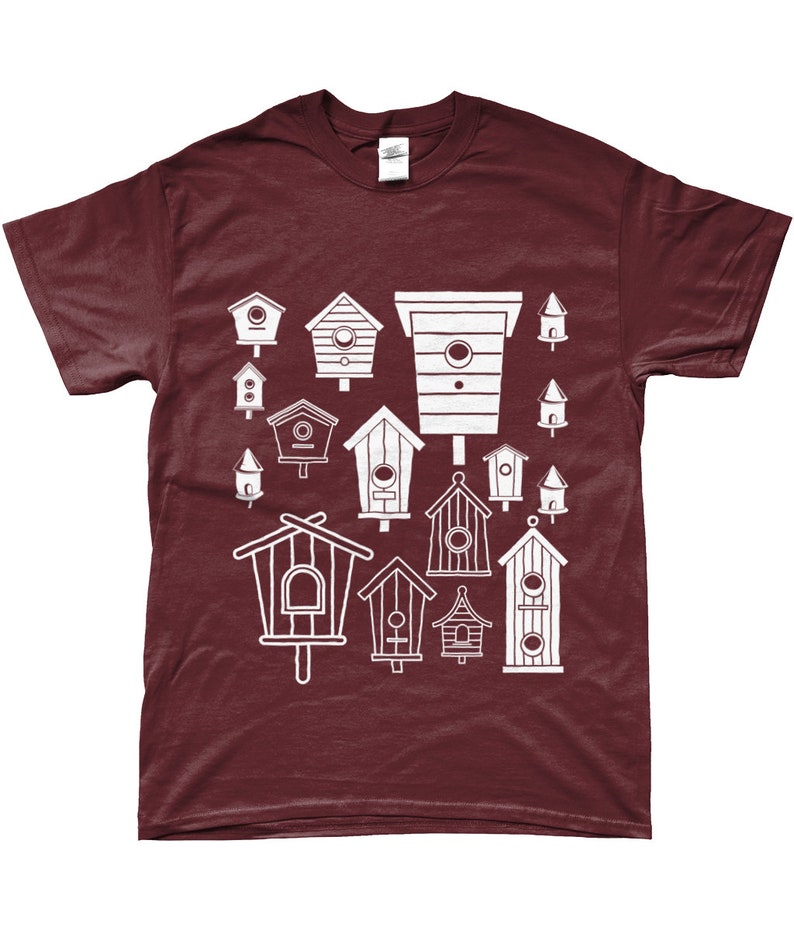 May include: A maroon t-shirt featuring a white design of various birdhouses in different shapes and sizes.