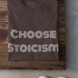 May include: A brown t-shirt with the text "CHOOSE STOICISM" printed in white with a retro font.