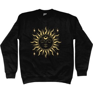 May include: Black sweatshirt with a gold sun and moon design. The sun has a face and is surrounded by stars.