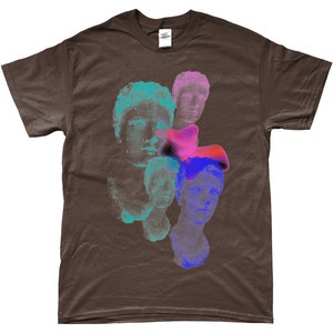 May include: A brown t-shirt with a graphic print of multiple colorful, abstract faces. The faces are layered on top of each other and appear to be made of stone.