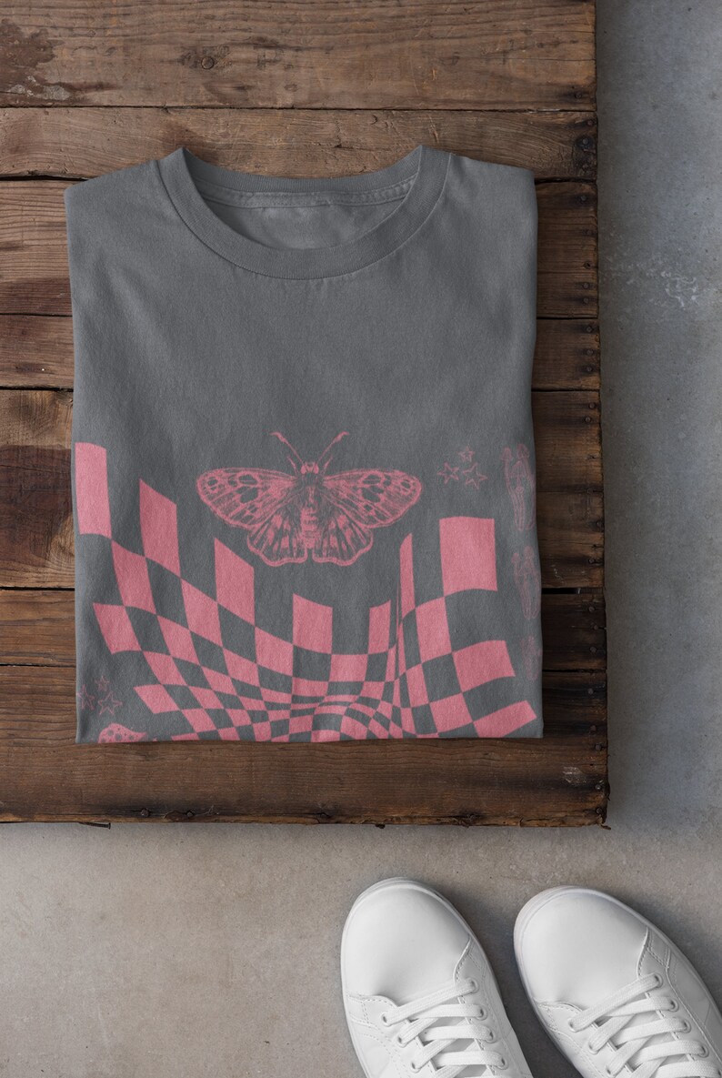May include: A gray t-shirt with a pink checkered pattern and a butterfly graphic. The pattern is distorted, creating a wavy effect.