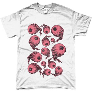 May include: White t-shirt with a graphic print of pink eyes with black outlines. The eyes are surrounded by a swirling, smoky design.