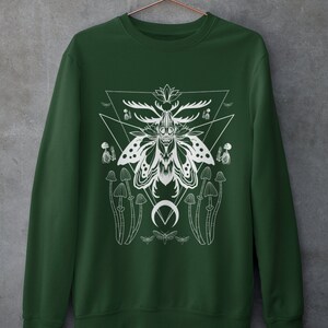 May include: A dark green sweatshirt with a white graphic print of a moth with antlers, mushrooms, and a crescent moon. The graphic is surrounded by a triangle.