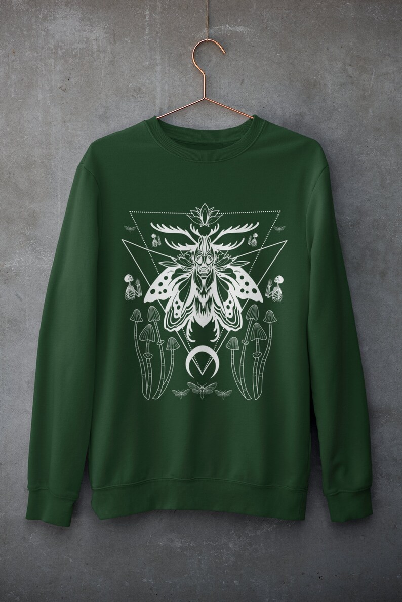 May include: A dark green sweatshirt with a white graphic print of a moth with antlers, mushrooms, and a crescent moon. The graphic is surrounded by a triangle.