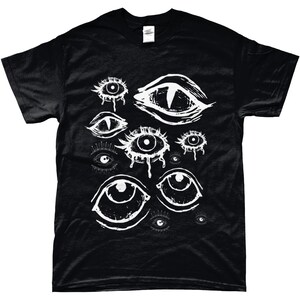 May include: Black t-shirt with a white graphic design of multiple stylized eyes. The eyes are drawn in a dripping, abstract style.
