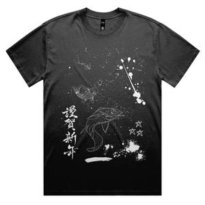 Puede incluir: Camiseta negra con un diseño gráfico blanco que presenta peces koi, estrellas y caracteres japoneses. El diseño tiene un efecto de salpicaduras, creando un aspecto dinámico y artístico. La camiseta es de cuello redondo.