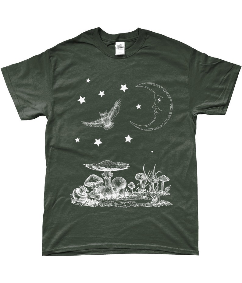 May include: A dark green t-shirt with a white graphic design of a crescent moon with a face, an owl flying, and mushrooms. There are stars scattered around the design.
