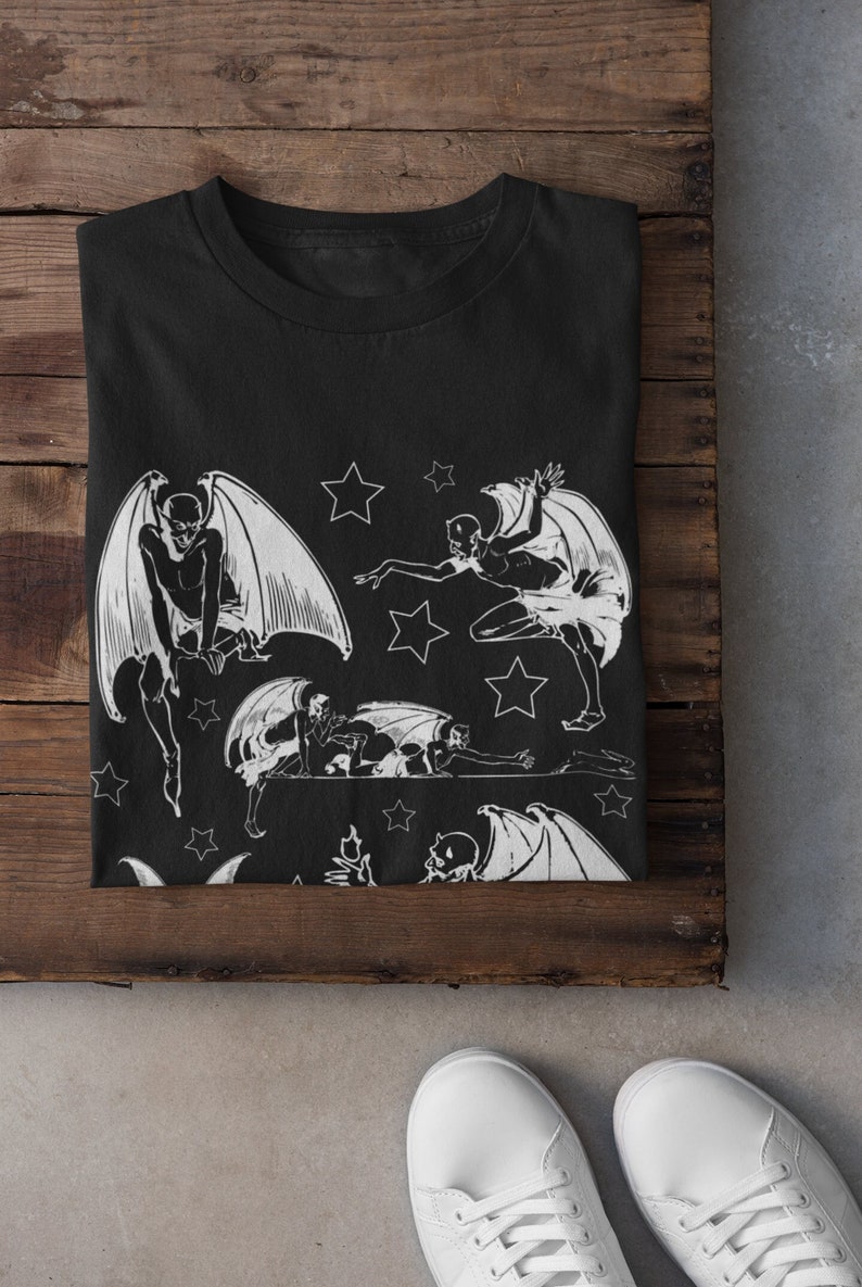 May include: Black t-shirt with a white print of multiple winged figures and stars.