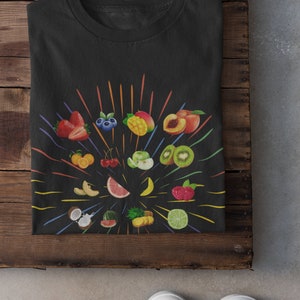 May include: Black t-shirt featuring a colourful fruit design. The fruits are arranged in a circle with a burst of colourful lines radiating outwards. The fruits include strawberries, blueberries, mango, peach, kiwi, oranges, cherries, apples, watermelon, pineapple, coconut, lime, and grapefruit.