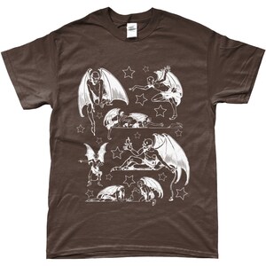 May include: A brown t-shirt with a white print of multiple winged figures with stars. The figures are in various poses, some flying, some sitting, and some lying down.