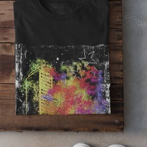 K&ouml;nnte beinhalten: Schwarzes T-Shirt mit einem bunten Grafikdruck einer Skyline und Sternen. Die Grafik hat einen abgenutzten, Vintage-Look.