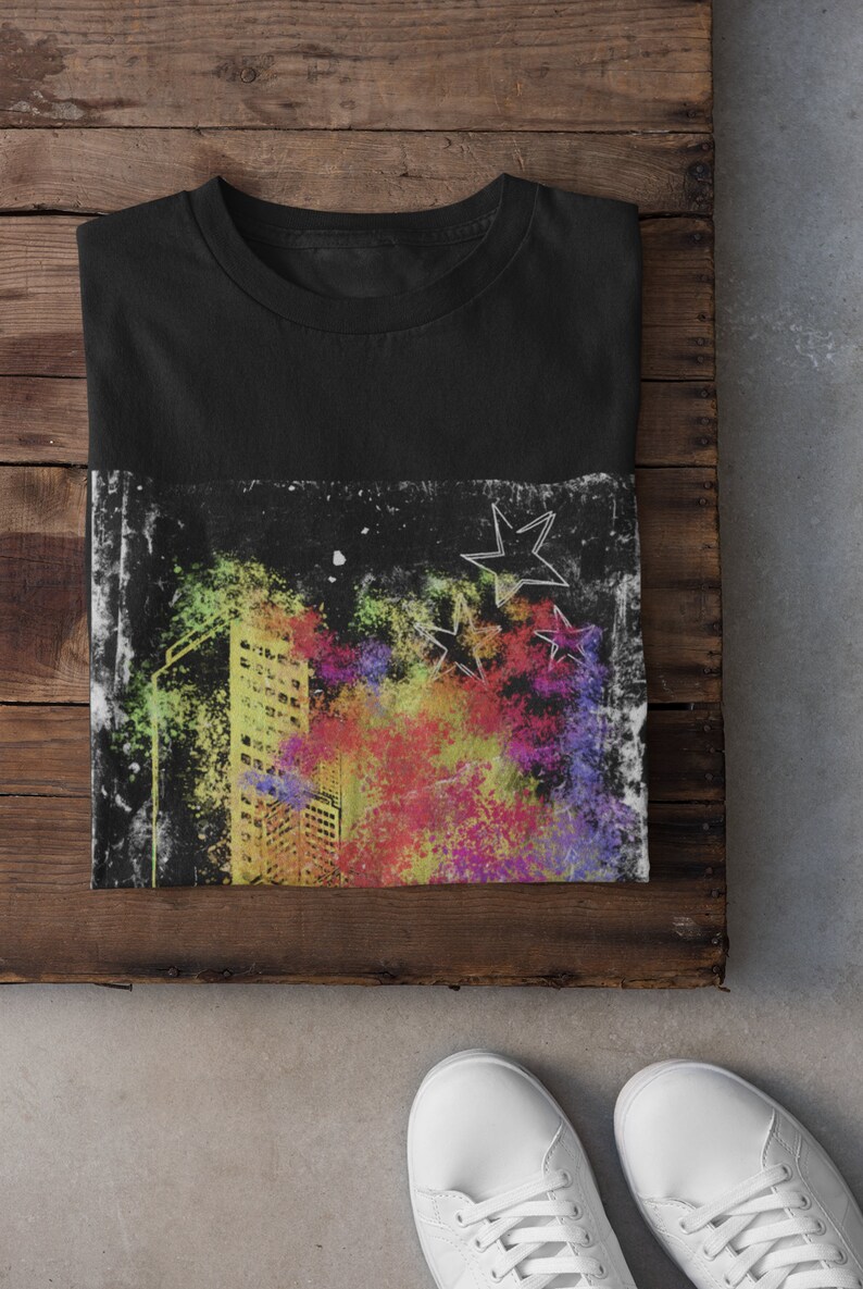 K&ouml;nnte beinhalten: Schwarzes T-Shirt mit einem bunten Grafikdruck einer Skyline und Sternen. Die Grafik hat einen abgenutzten, Vintage-Look.