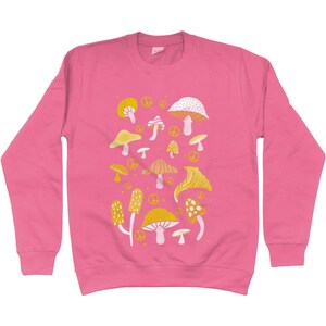 Puede incluir: Sudadera rosa con un patr&oacute;n de setas amarillas y blancas. Las setas son de varias formas y tama&ntilde;os. Hay signos de paz dispersos por todo el dise&ntilde;o.