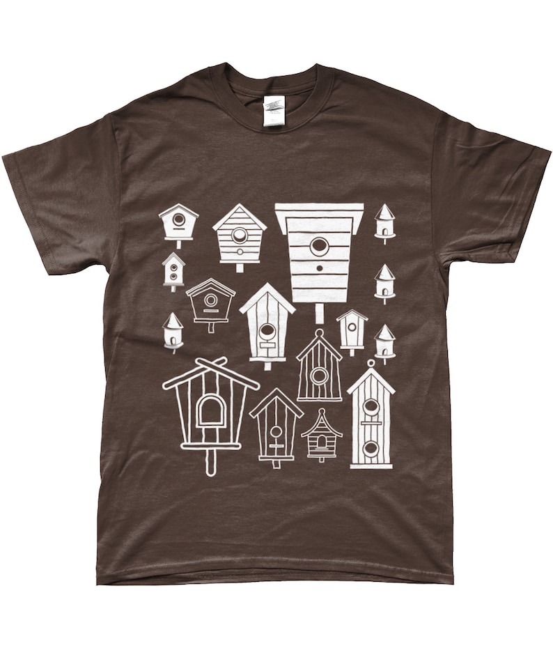 May include: A brown t-shirt featuring a white design of various birdhouses in different shapes and sizes.