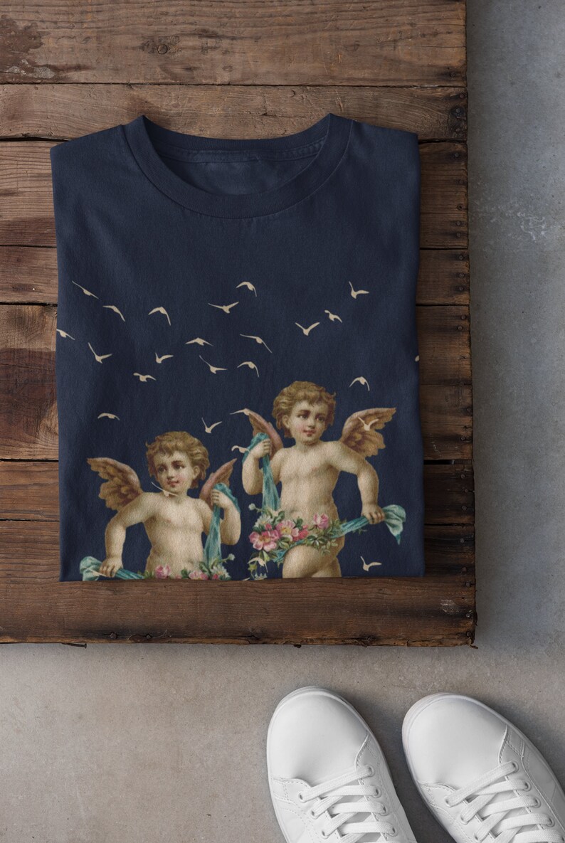May include: A navy blue t-shirt with a print of two cherubs with wings and floral garlands, flying against a background of white birds.