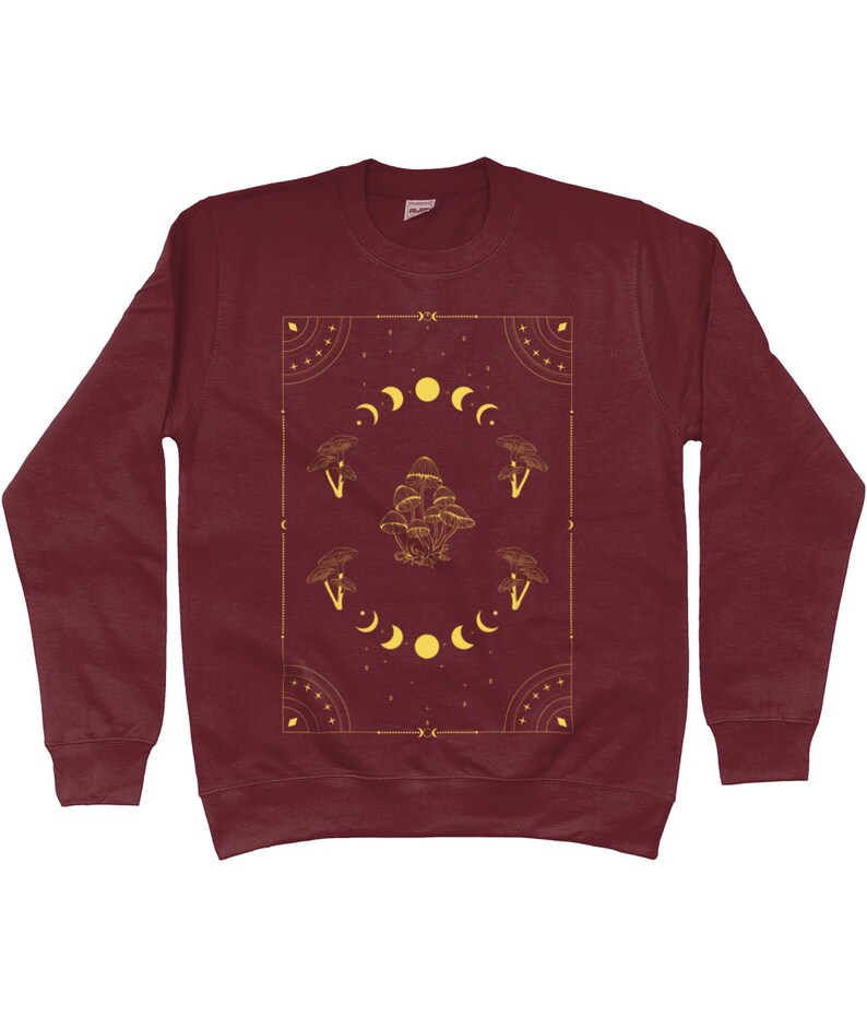 May include: Burgundy sweatshirt with a gold graphic design featuring mushrooms and moons in a geometric frame.