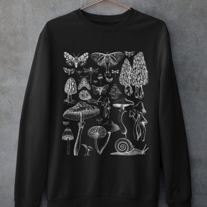 Pode incluir: Camisola de moletom preta com uma estampa gr&aacute;fica branca de v&aacute;rios cogumelos, borboletas e um caracol. O gr&aacute;fico &eacute; uma ilustra&ccedil;&atilde;o de estilo vintage.