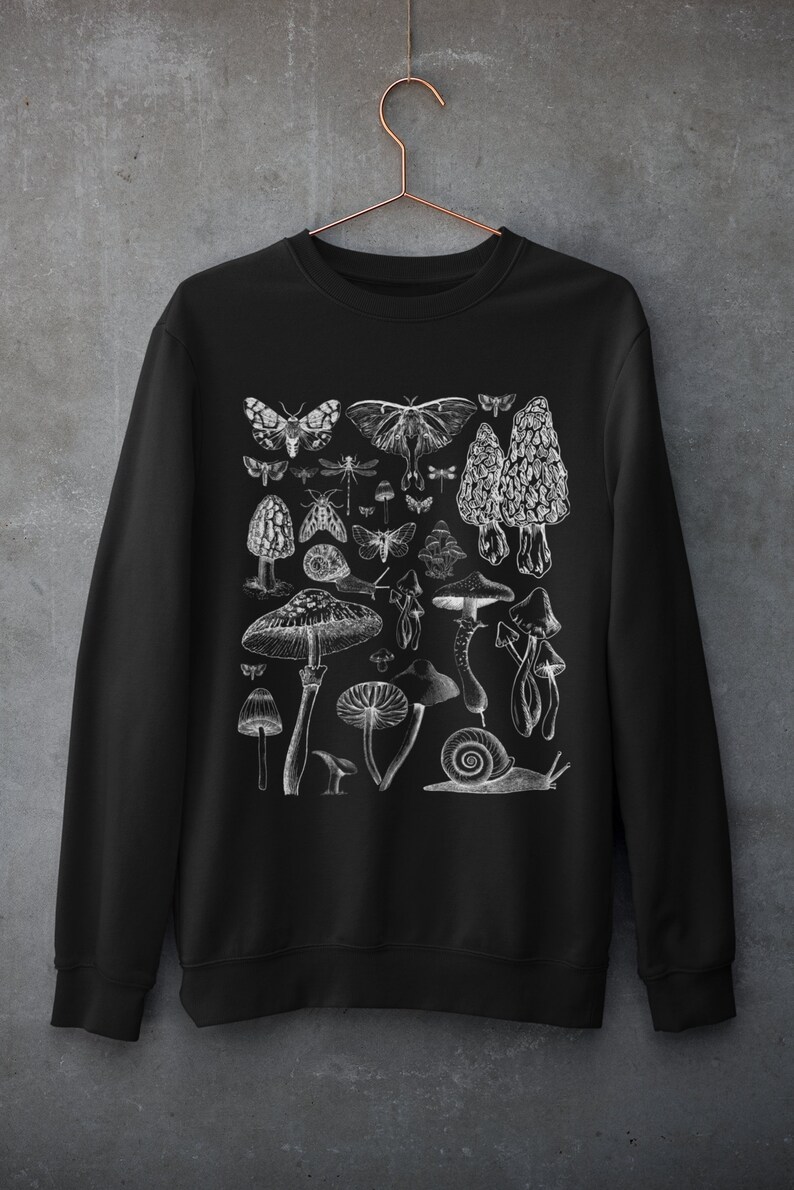 Pode incluir: Camisola de moletom preta com uma estampa gr&aacute;fica branca de v&aacute;rios cogumelos, borboletas e um caracol. O gr&aacute;fico &eacute; uma ilustra&ccedil;&atilde;o de estilo vintage.