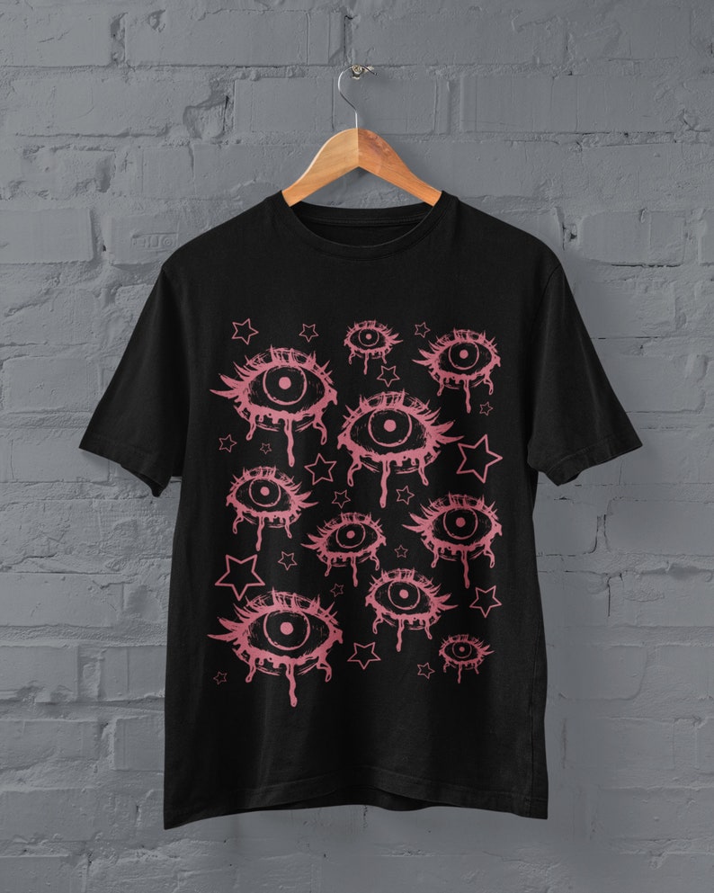 May include: Black t-shirt with a pink graphic print of multiple dripping eyes and stars.