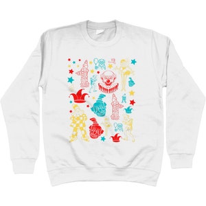 May include: White long-sleeve sweatshirt with a colorful pattern of clowns, stars, and hats. The design features a variety of clown faces, hats, and other circus-related imagery.