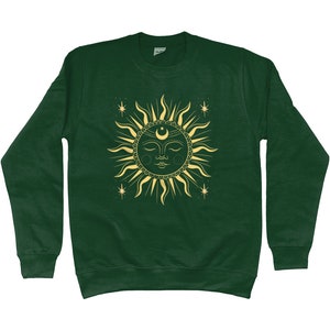 May include: A dark green sweatshirt with a gold sun and moon design. The sun has a face and is surrounded by stars.