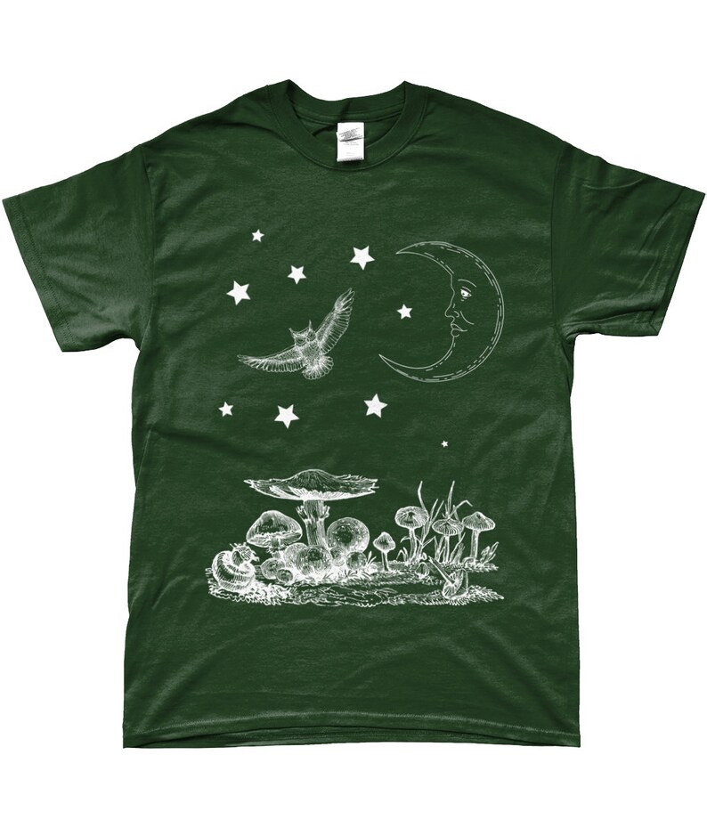 May include: A dark green t-shirt with a white graphic design of a crescent moon with a face, an owl flying, and mushrooms in a forest setting.