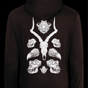 May include: A black hoodie with a white design of animal skulls on the back. The design features a deer skull in the center with two bird skulls and two monkey skulls on either side.