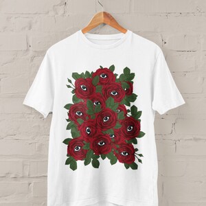 May include: White t-shirt with a graphic print of red roses with eyes in the center of each rose.