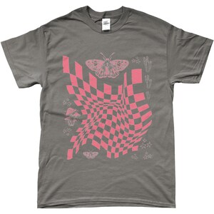 May include: A dark gray t-shirt with a pink and white checkered pattern, a butterfly, and stars. The checkered pattern is distorted and appears to be moving.